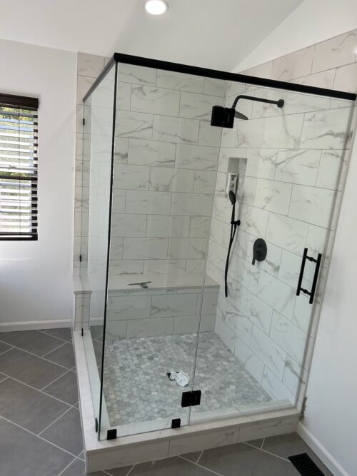A walk-in shower with marble tiles and glass enclosure.