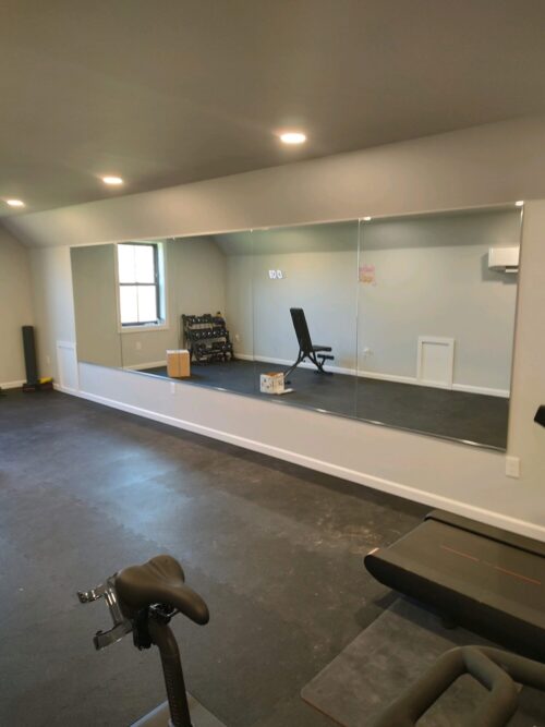 A residential work out room with large mirrors on one wall.