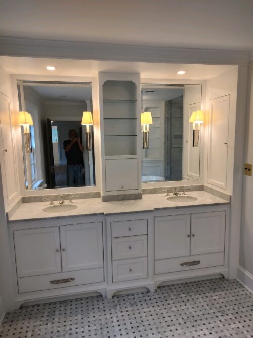 A bathroom with a white double vanity and large mirrors